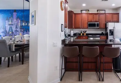 a kitchen with a counter and a dining room with a table at Magical 6BR Family Retreat with Pool Near Disney in Orlando