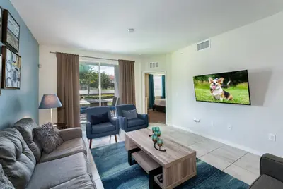 a living room with a couch and a tv on a wall at Themed 3-bed 2 bath condo at Storey Lake Resort in Kissimmee