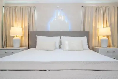 a bedroom with a large white bed with two lamps at 2557 Awesome Family 4BD Townhouse located at Storey Lake in Kissimmee