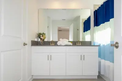 a bathroom with a sink and a large mirror at 2557 Awesome Family 4BD Townhouse located at Storey Lake in Kissimmee