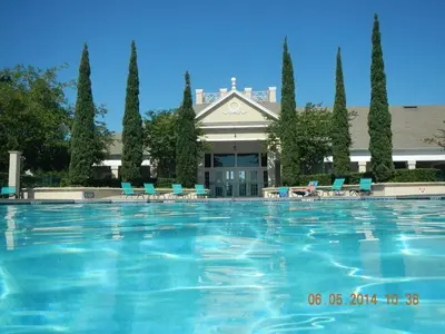 a large swimming pool with chairs and a building at Venetian Bay Villages in Kissimmee