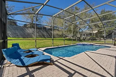 a swimming pool with two chairs and a glass house at Amazing House Amazing Amenities in Orlando