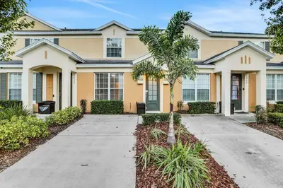 a house with a palm tree in front of it at Elegant Townhome w Water Park near Disney Parks in Orlando