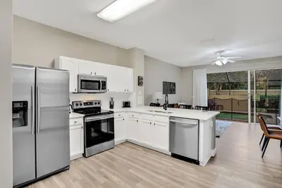 a kitchen with white cabinets and stainless steel appliances at Elegant Townhome w Water Park near Disney Parks in Orlando