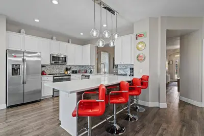 a kitchen with white cabinets and red bar stools at 6BR Fun in the Sun with FREE water park in Orlando