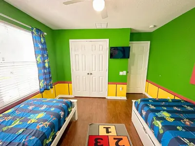 a childs bedroom with two beds and green walls at Family Fun 6BR Poolside w Water Park Game Room in Orlando