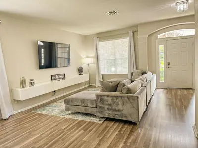 a living room with a couch and a flat screen tv at Family Fun 6BR Poolside w Water Park Game Room in Orlando