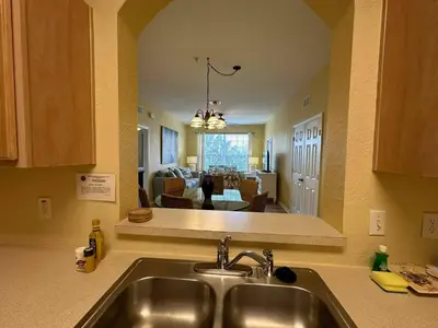 a kitchen with a sink and a living room at Delight Condo Water Park Near Disney Parks in Orlando