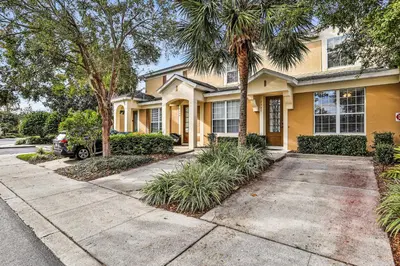 a yellow house with palm trees and a driveway at Water Park Haven: Spacious 3BR Windsor Hills in Orlando