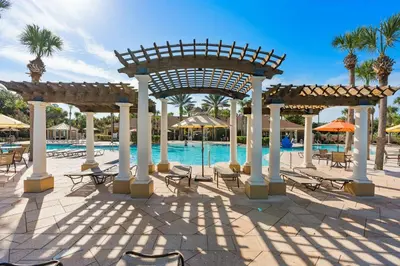 a pool with tables and chairs and a pavilion at Elegant Getaway Windsor Hills Condo w Water Park in Orlando