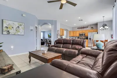 a living room with brown leather furniture and a kitchen at Family Fun Haven: Spacious Villa Water Park in Orlando