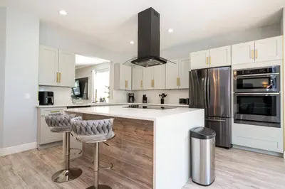 a kitchen with white cabinets and a kitchen island with bar stools at FREE Water Park Fun Included Large Resort Home in Orlando