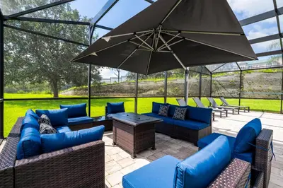 a patio with blue couches and an umbrella at FREE Water Park Fun Included Large Resort Home in Orlando