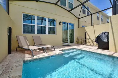 a swimming pool with two chairs next to a house at Family Paradise 4BR Compass Bay Townhome Sleeps 11 in Kissimmee