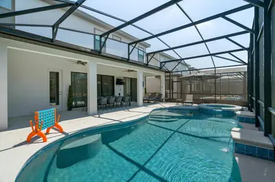 a swimming pool with a chair and a house at Luxury Living: 6BR Condo near SeaWorld ICON Park in Orlando
