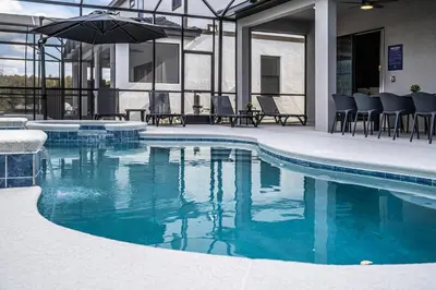 a swimming pool with chairs and an umbrella at Themed Retreat 6BR w Magical Rooms Private Pool in Orlando
