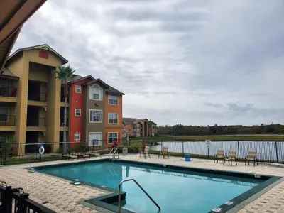 a swimming pool with chairs and a building at Villa del Sol in Kissimmee