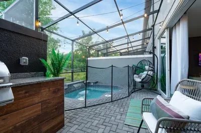 a patio with a swimming pool in a glass house at Star Wars and Frozen, Pool, 10 min to Disney in Kissimmee