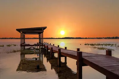 a dock on a lake with the sunset in the background at 4 Rooms, Lake, Pool, Hot Tub, Putt-Putt in Orlando