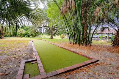 a garden with a green lawn and trees in a park at Themed Speak Easy with Pool, Hot Tub, & Lake in Orlando