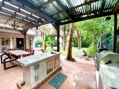 a patio with an outdoor kitchen and a table at Themed Speak Easy with Pool, Hot Tub, & Lake in Orlando