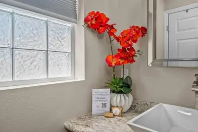 a bathroom with a vase with red flowers on a counter at New Design-Movie Night Bar-Fire Pit-Hammocks-Games in Orlando