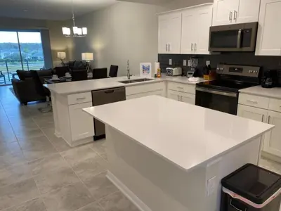 a kitchen with white cabinets and a white counter top at Comfortable 2BR Condo w/ Lake Views in Kissimmee