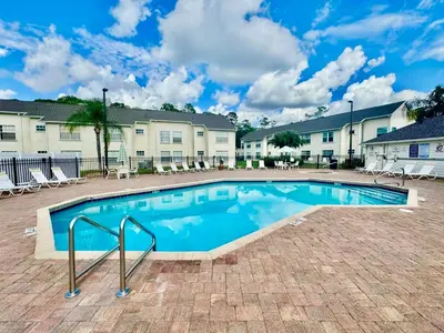 a swimming pool in a courtyard with chairs and buildings at Grand Luxury 3BR Penthouse near Disney Parks in Kissimmee