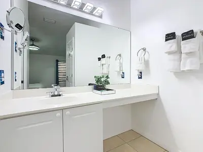 a white bathroom with a sink and a mirror at The Galactic Getaway, 3Bed, 2Bath Apartment, Free Parking, Heated Pool in Kissimmee