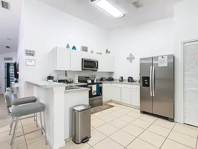 a kitchen with a stainless steel refrigerator and a counter at The Galactic Getaway, 3Bed, 2Bath Apartment, Free Parking, Heated Pool in Kissimmee