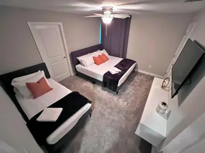 a small room with two beds and a television at Spacious 5BR Villa w/ Private Pool Near Disney & Orlando! in Kissimmee