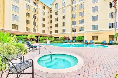 a swimming pool with chairs and a building at Condo with Pool & Hot Tub - Universal Studios in Orlando