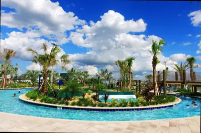 a resort pool with palm trees and people in it at Stunning 4Bd Close to Disney with Pool at Storey Lake 4369 in Kissimmee