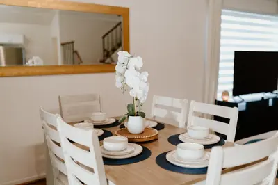 a dining room table with white dishes and a vase with flowers at Luxury Private Pool Villa near Disney with Fire Pit, Game Room & More in Kissimmee