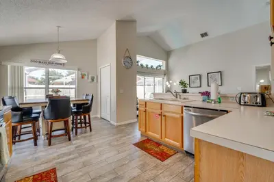 a kitchen and living room with a table and chairs at 15 Mi to Universal Home with Pool in Kissimmee
