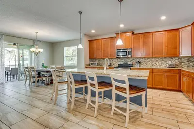 a kitchen with wooden cabinets and a table with chairs at Private Pool and Game Room Family Vacation Rental in Kissimmee