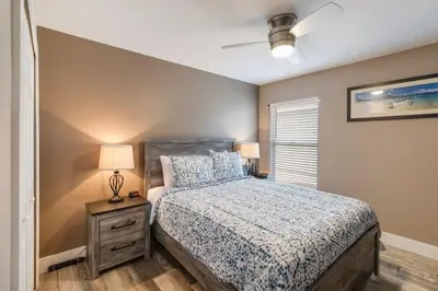 a bedroom with a bed with a nightstand and a window at Vacation Home near Disney World! in Kissimmee