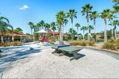 a picnic table on a beach with palm trees at Vacation Home near Disney World! in Kissimmee