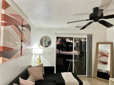 a living room with a black couch and a ceiling fan at Modern 2BR Lakeview Near Orlando Airport Free Parking in Orlando