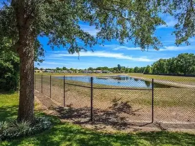 a fence with a tree next to a lake at Modern 2BR Lakeview Near Orlando Airport Free Parking in Orlando