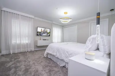 a white bedroom with a bed and a tv at Storey Lake 4Q/3B acesso Resort e Piscina Priv. in Kissimmee