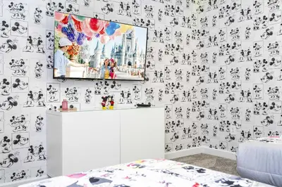 a living room with a tv on a wall covered in wallpaper at Storey Lake 4Q/3B acesso Resort e Piscina Priv. in Kissimmee