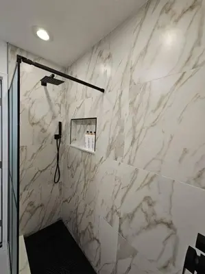 a bathroom with a shower and a marble wall at Newly Renovated Modern Studio in Oviedo