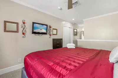 a bedroom with a red bed with a tv on the wall at Tranquil Haven 2BD 2BA Paradise 10min to Orlando's Best Theme Parks in Orlando