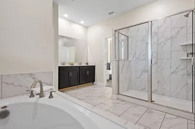 a white bathroom with a tub and a shower at 4561 Majestic 9BD Kingdom Retreat Near Disney in Kissimmee