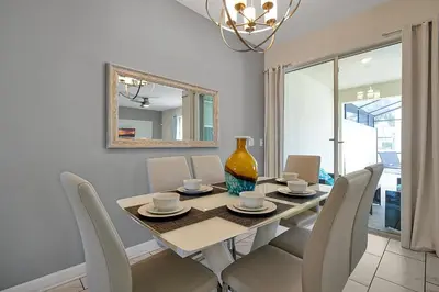 a dining room with a table with chairs and a vase at Storey Lake Home: Pool, Gym, Lazy River & near Disney in Kissimmee
