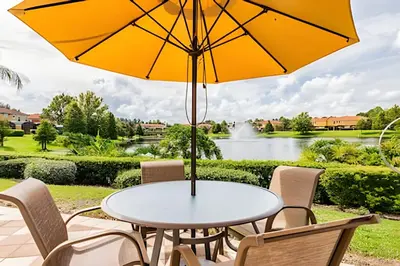 a table and chairs with an umbrella and a pond at 3Q/2.5B ✰ Jacuzzi ✰ Cama King in Kissimmee