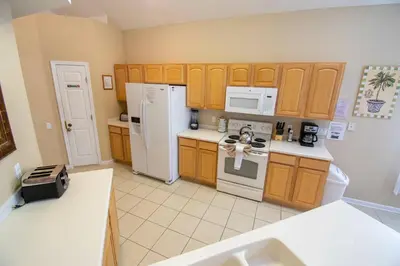 a kitchen with wooden cabinets and white appliances at Stunning 6 bedroom vacation villa in Orlando