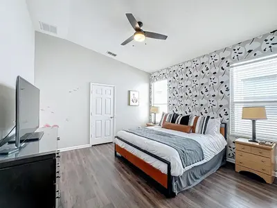 a bedroom with a bed and a flat screen tv at Windsor Palms Minion, Princess, Mickey, Pool Home in Kissimmee