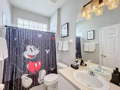 a bathroom with a mickey shower curtain with a toilet and sink at Windsor Palms Minion, Princess, Mickey, Pool Home in Kissimmee